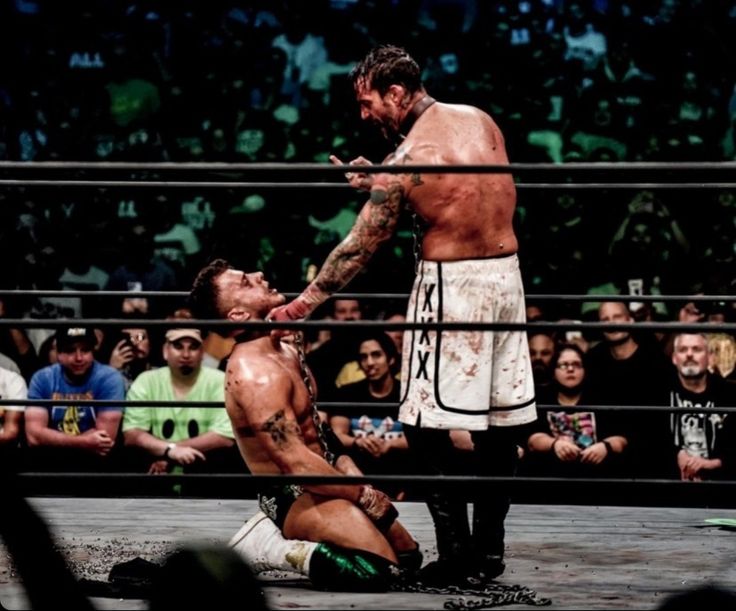 two men wrestling in an arena with people watching