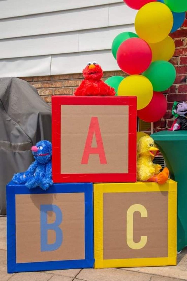 colorful blocks with letters and balloons in front of a building that says abc, c