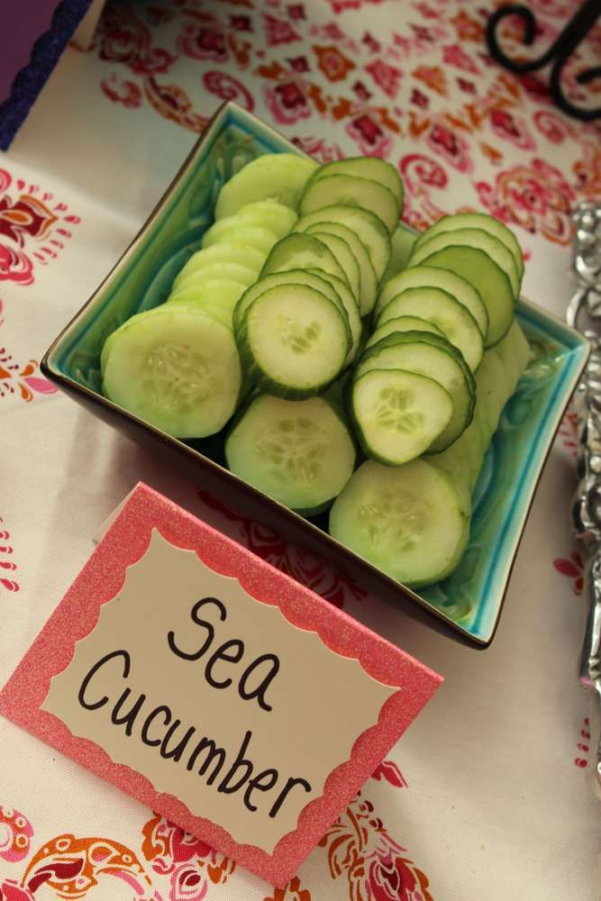 cucumbers are arranged on a plate next to a sign that says sea cucumber