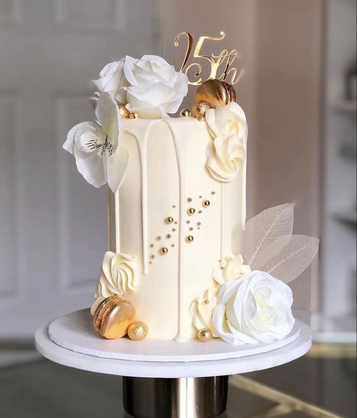 a white wedding cake with gold decorations and flowers