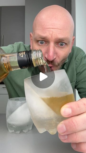 a man is pouring something into a glass in front of him and looking at the camera