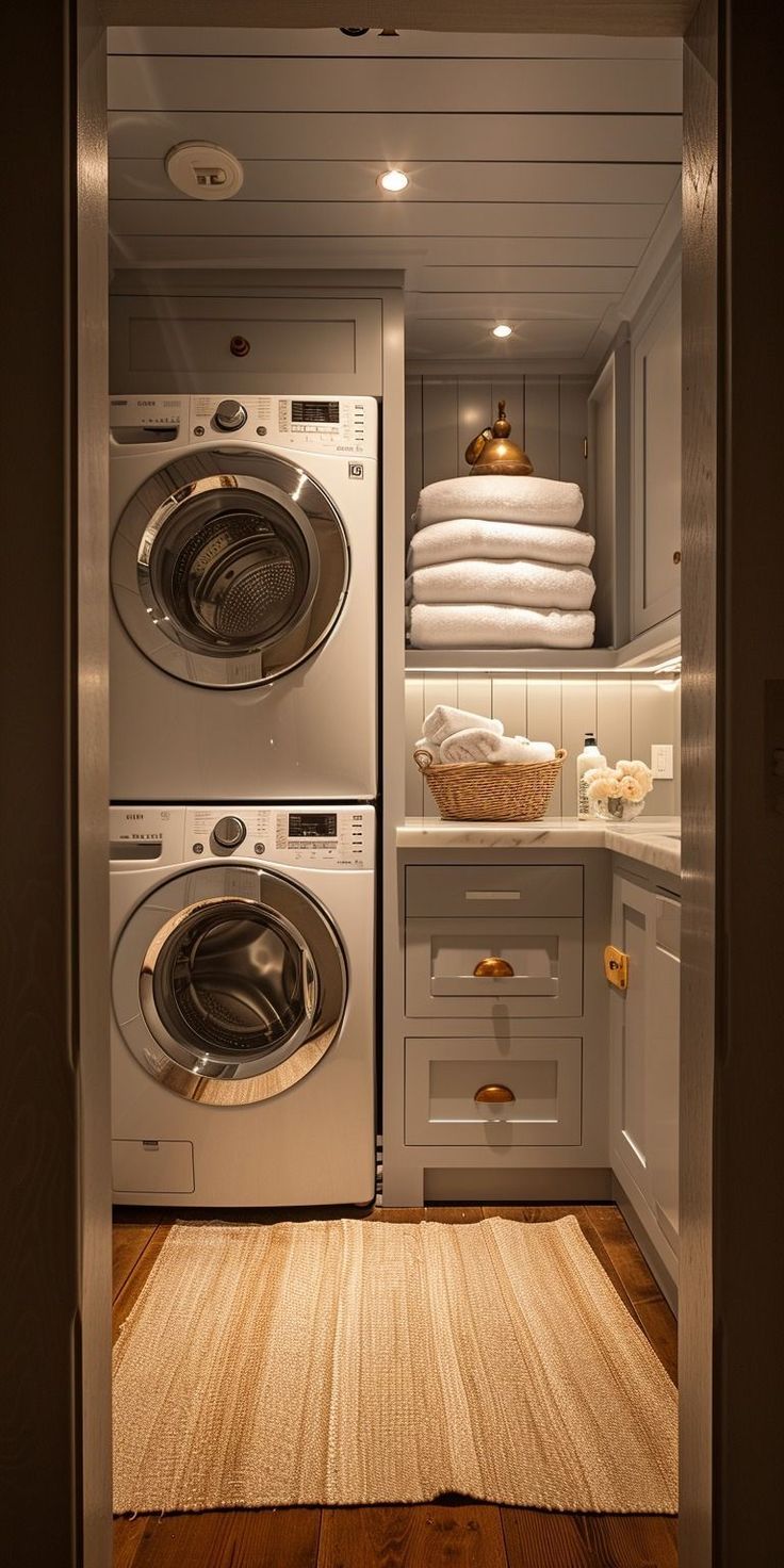 a washer and dryer in a small room next to each other with towels stacked on the shelves