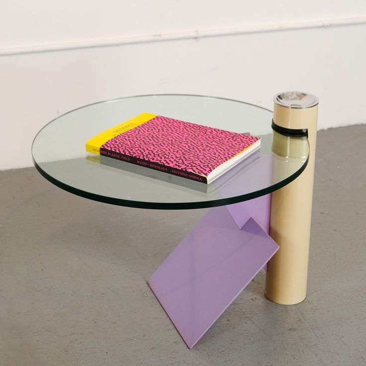 a glass table with a pink book on top and a purple object next to it