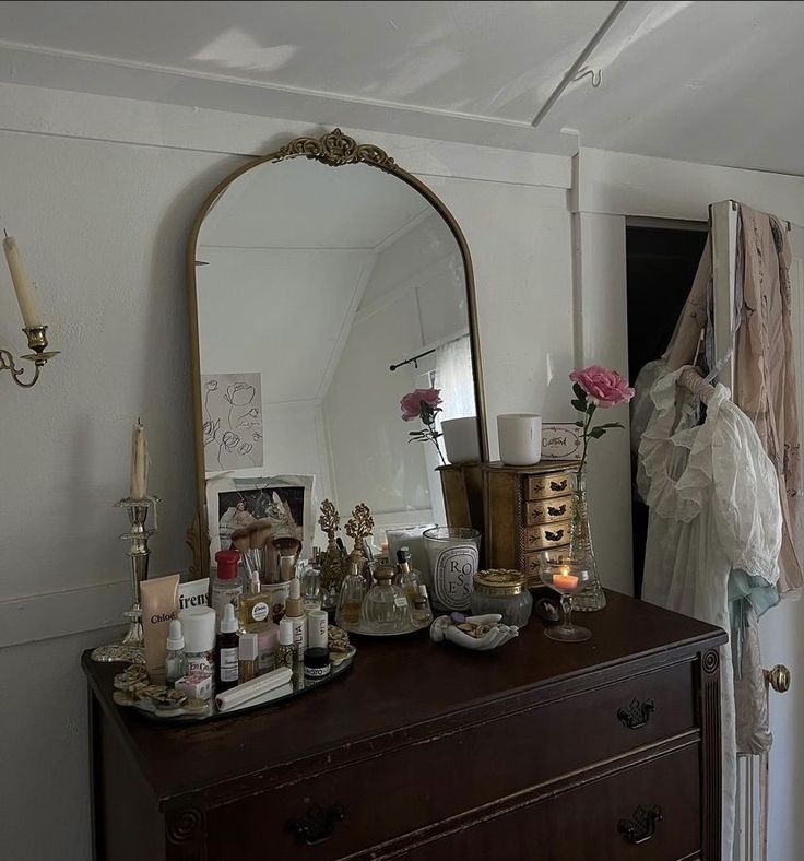 a dresser with a mirror, candles and other items on it