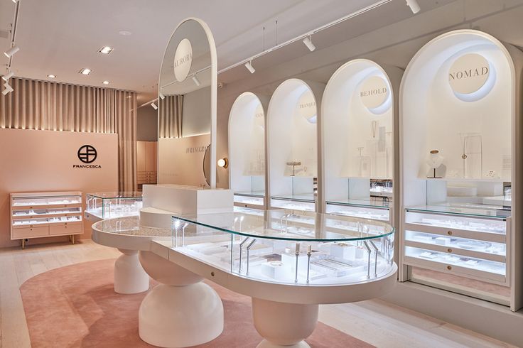 the inside of a jewelry store with glass display cases and round tables on each side