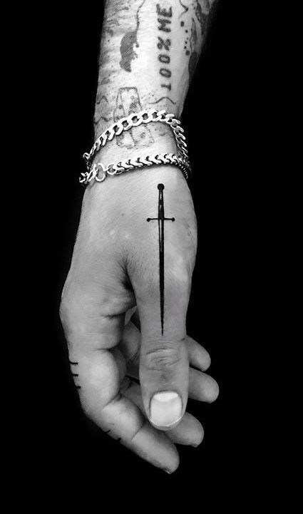 a person's hand with a cross tattoo on it and a chain around the wrist