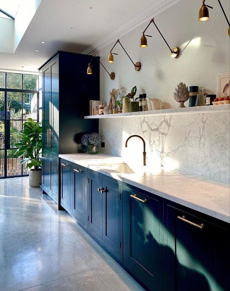 a kitchen with marble counter tops and blue cabinets, along with hanging lights above the sink