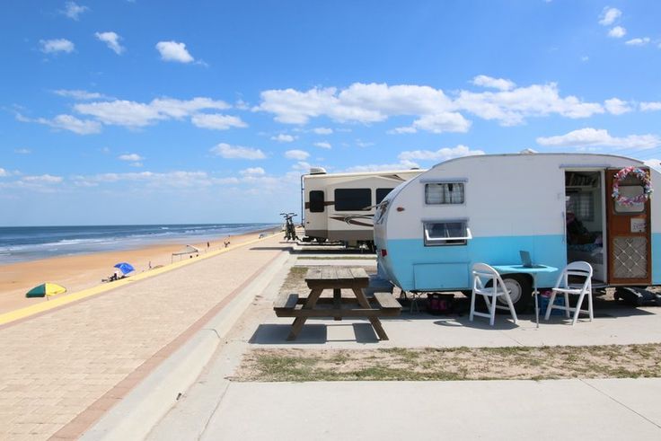 an rv park on the beach with picnic tables and chairs