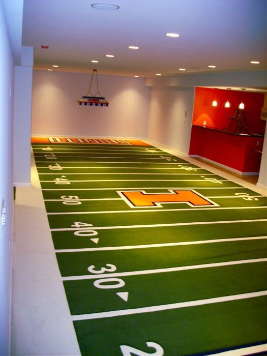 an empty football field with lights on and numbers painted on the ground in front of it