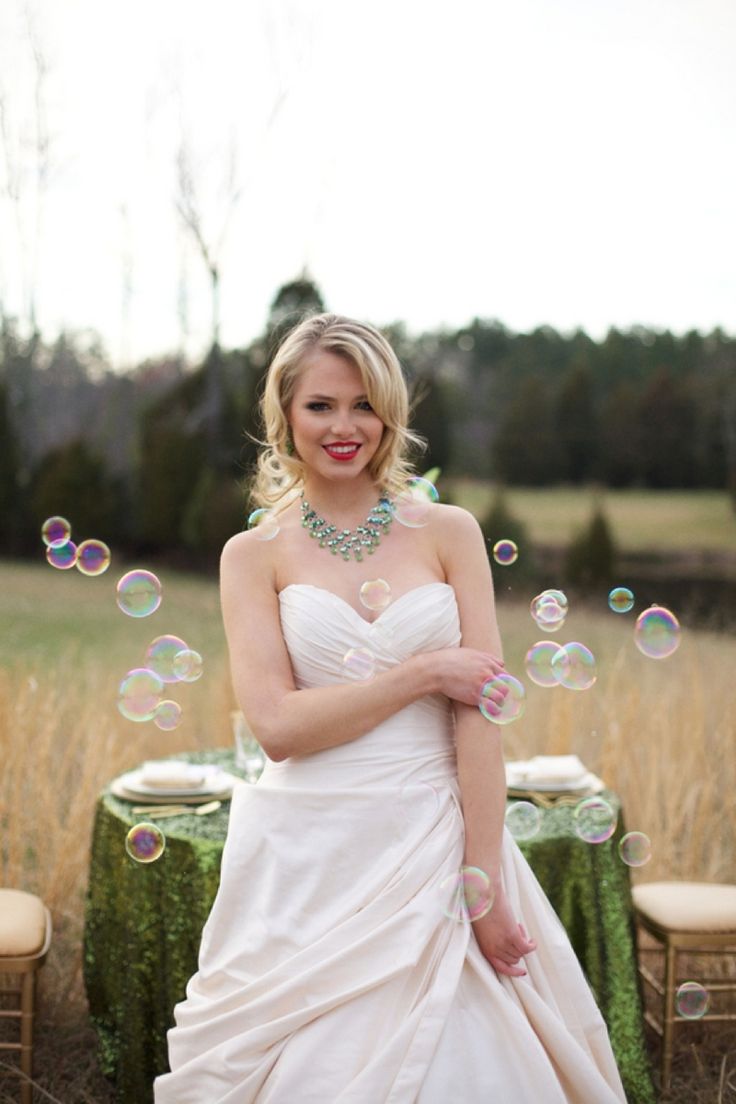 a woman in a white dress is standing near a table with soap bubbles on it