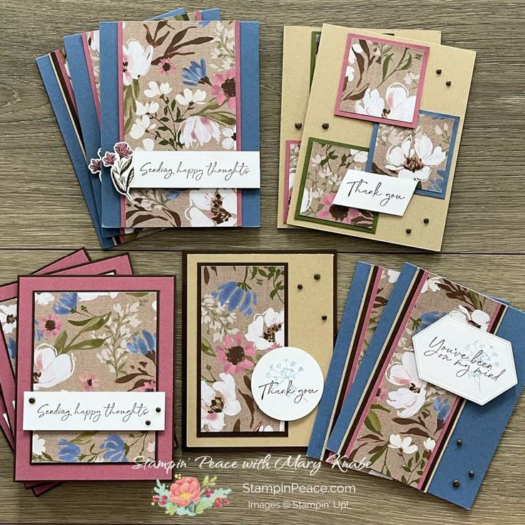 some cards with flowers on them sitting on top of a wooden table next to each other