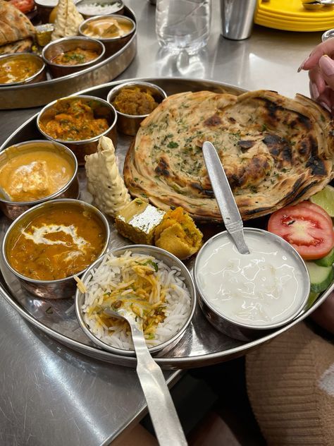 a tray filled with lots of food on top of a metal table next to other dishes