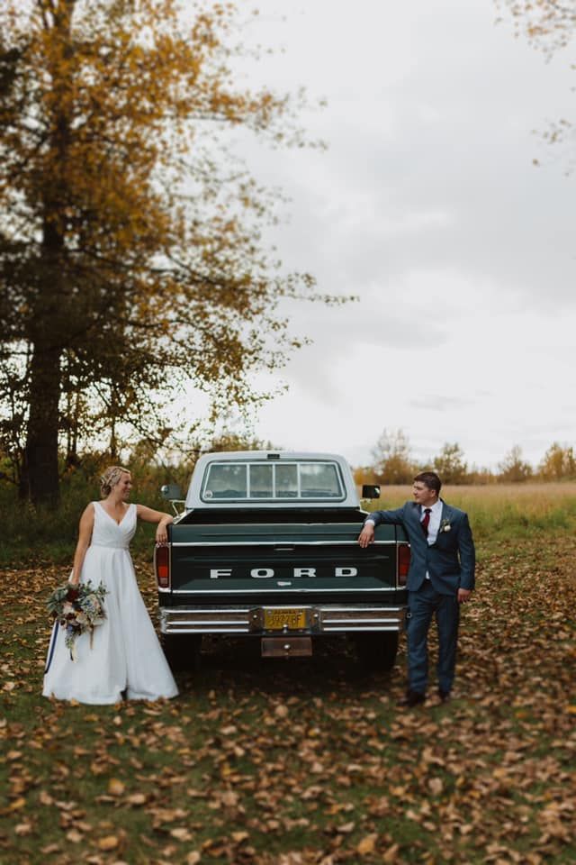 a bride and groom standing next to a truck