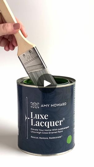 a person is holding a paint brush in a blue can with the word luxury on it