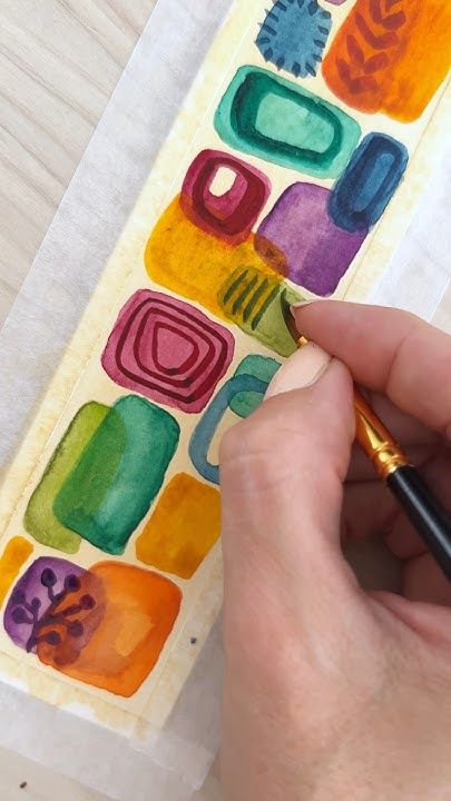 a person is drawing letters on a piece of paper with watercolors and a pen