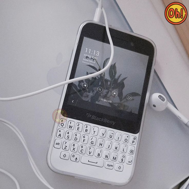 a cell phone hooked up to an earbud on top of a white table