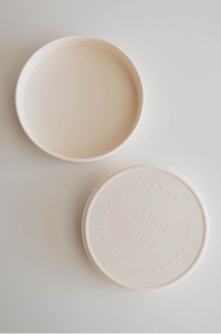 A round, ivory, BPA-free silicone Training Plate by forever french baby features both a lid and a base. The base is open-ended, while the lid is imprinted with symbols indicating it's safe for dishwashers, microwaves, and freezers—making it the perfect companion for mealtime. Toddler Plates, French Baby, Women Set, Burp Cloths, Say Goodbye, Baby Month By Month, Meal Time, Food Safe