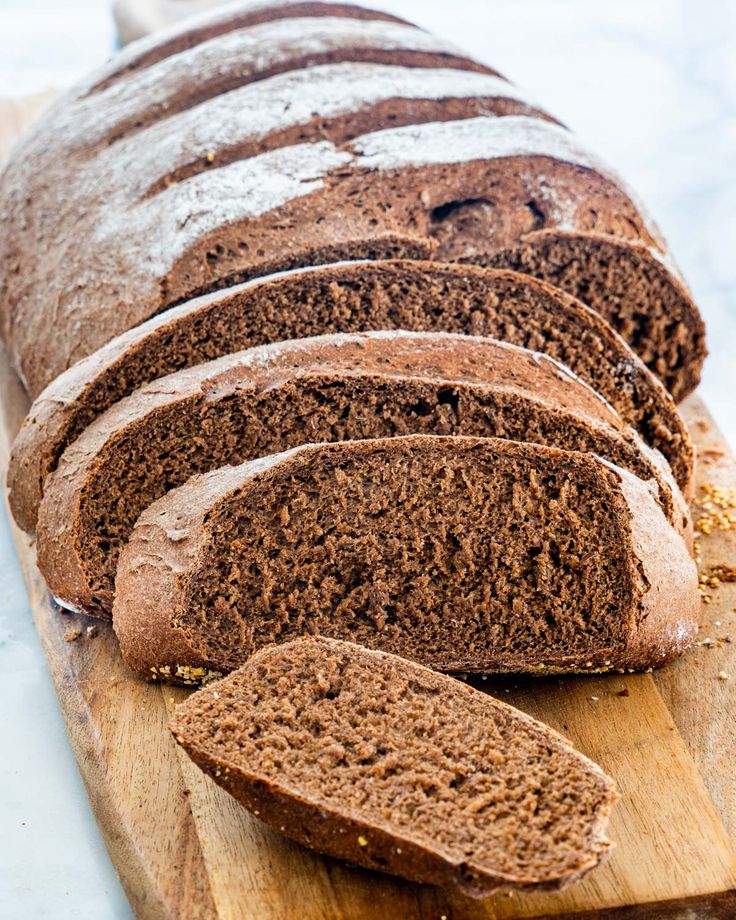 a loaf of brown bread sitting on top of a wooden cutting board