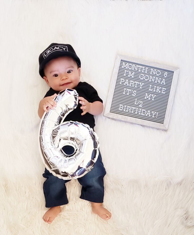 a baby is holding a foil number six balloon