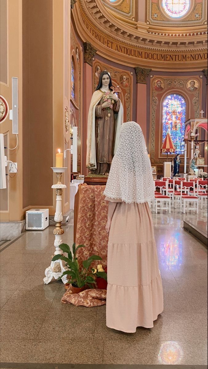 a woman standing in front of a church alter with a statue on it's side