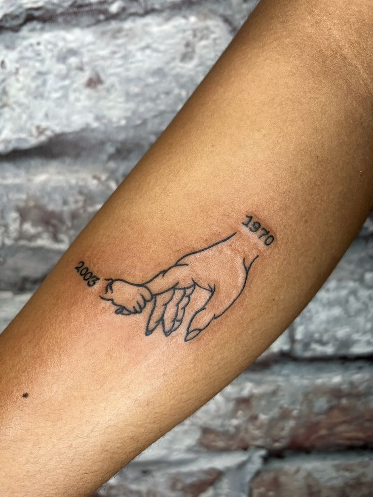 a person with a tattoo on their arm holding the hand of another person's finger