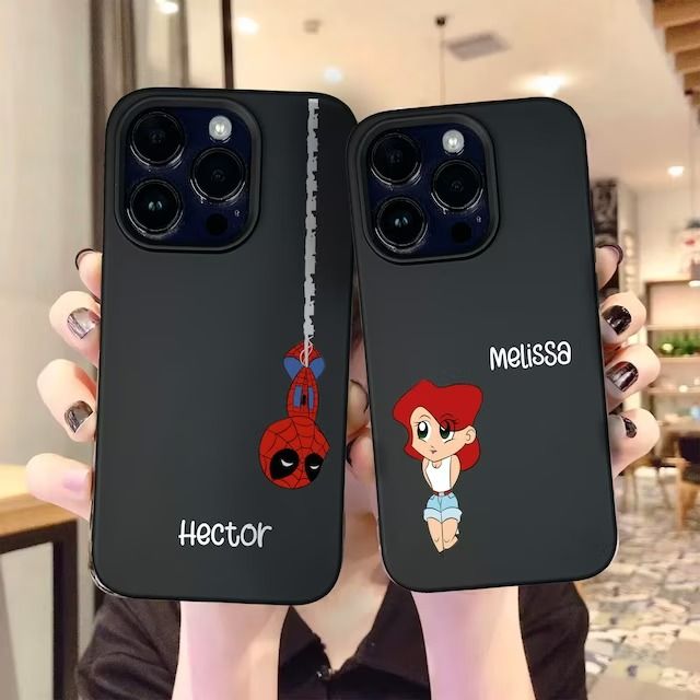 someone holding up two cell phones with cartoon characters on them, and the same phone case