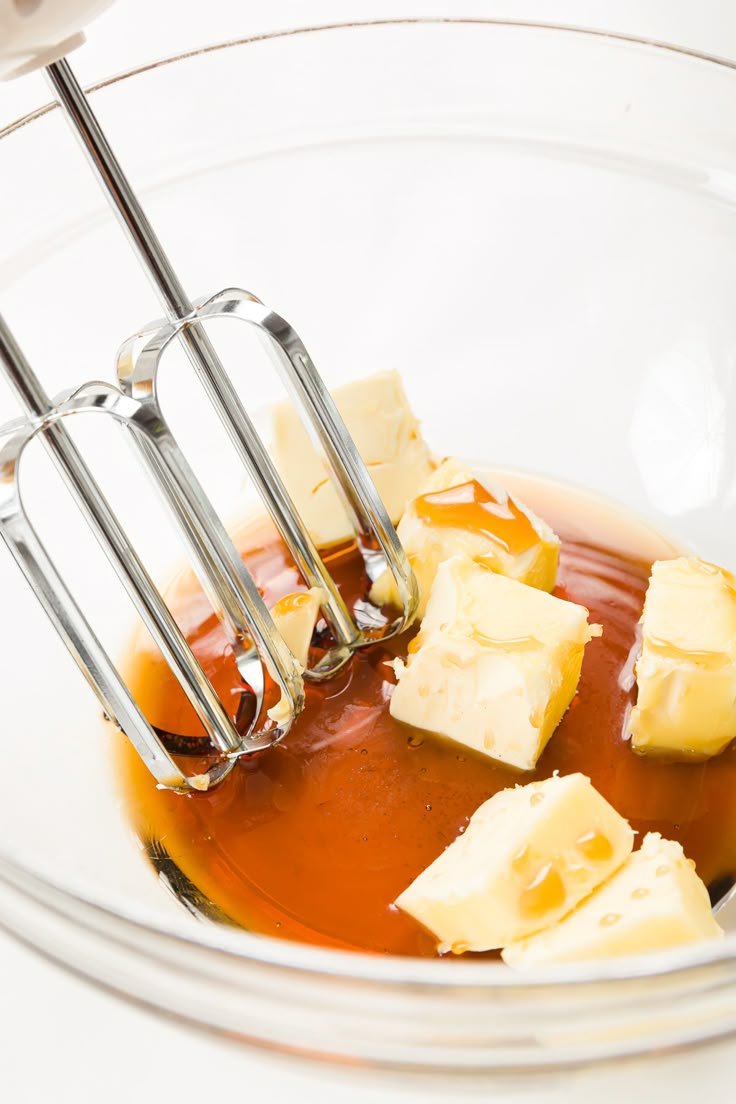 a whisk is being used to stir butter and sauce in a glass bowl