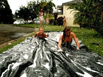 two people are laying on a tarp in the yard while another person is standing next to them