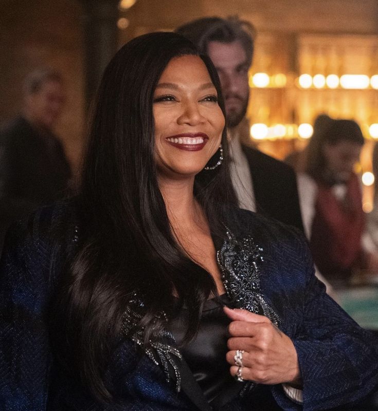 a woman with long black hair smiling and standing in front of other people at a party