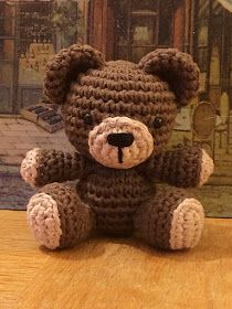 a brown crocheted teddy bear sitting on top of a wooden table