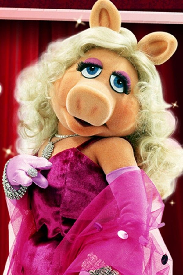 the miss piggy doll is dressed in pink and has her arms around her chest