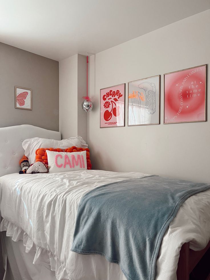 a white bed sitting in a bedroom next to two pictures on the wall above it