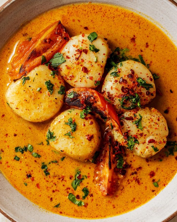 a white bowl filled with food and garnished in red sauce on top of a wooden table