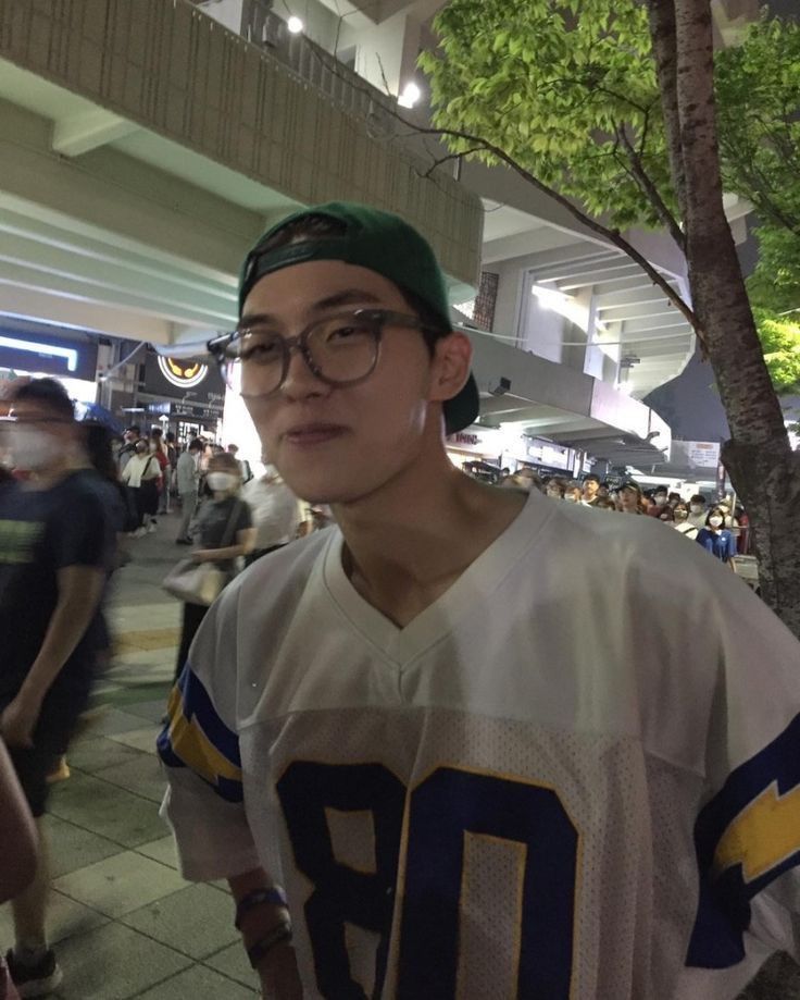 a young man wearing glasses and a football jersey is standing in front of a crowd