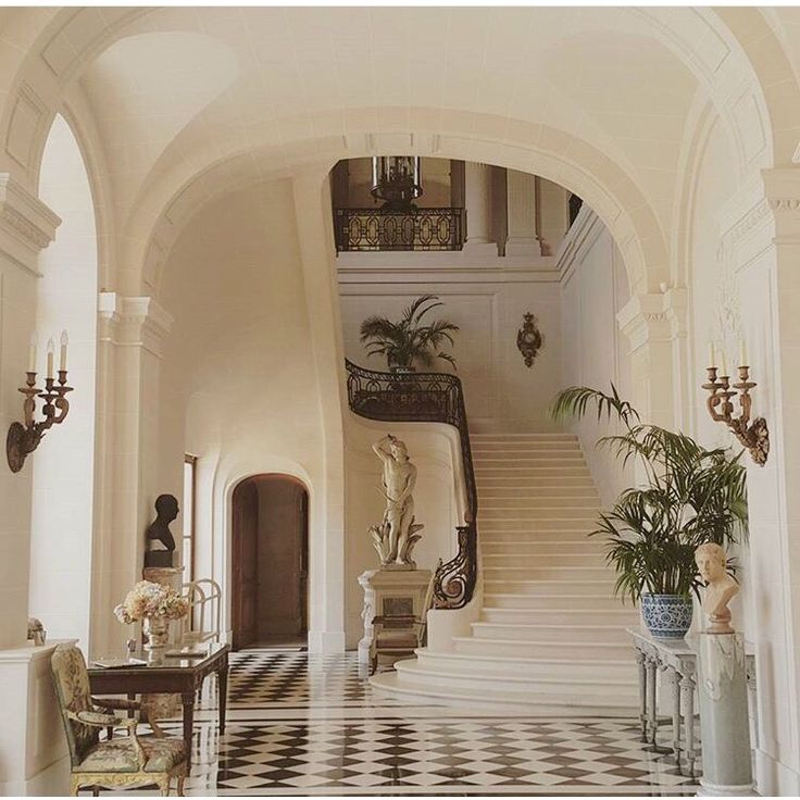 an ornate entry way with stairs and potted plants