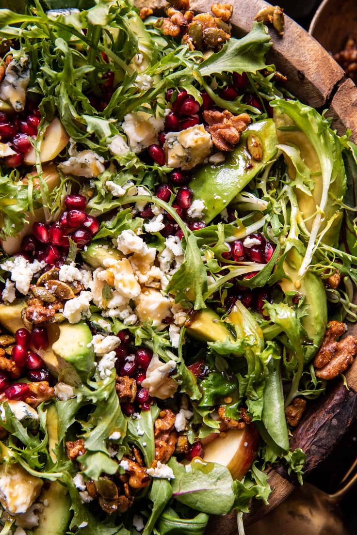 a salad with apples, avocado, walnuts and feta cheese in a wooden bowl