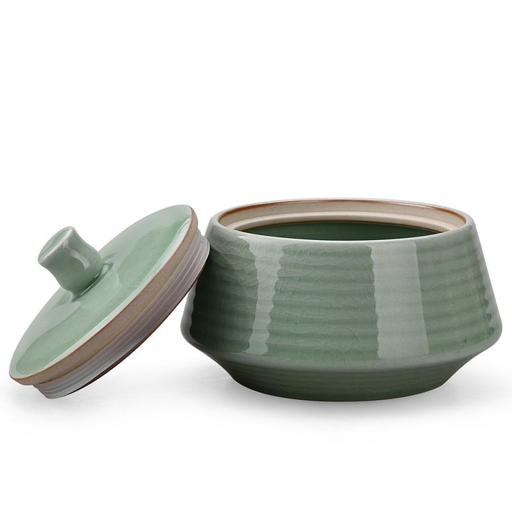 a green bowl with a lid sitting next to it