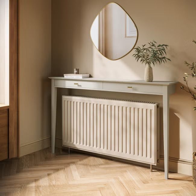 a white radiator sitting on top of a wooden floor next to a mirror