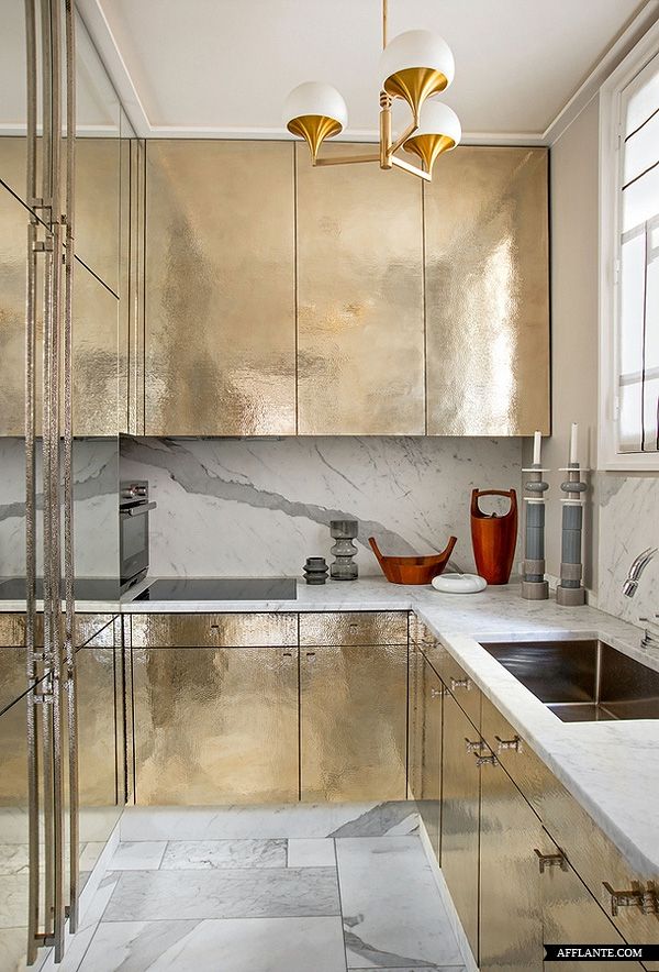 a metallic kitchen with marble counter tops and gold cabinetry is pictured in this image