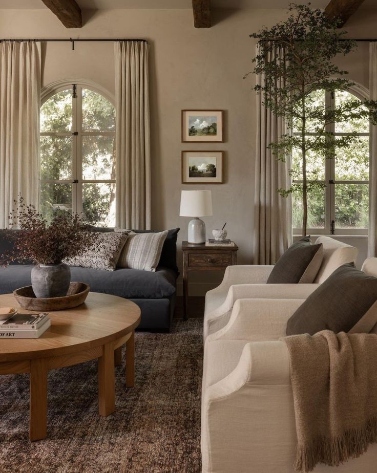 a living room with two couches and a coffee table in front of three windows