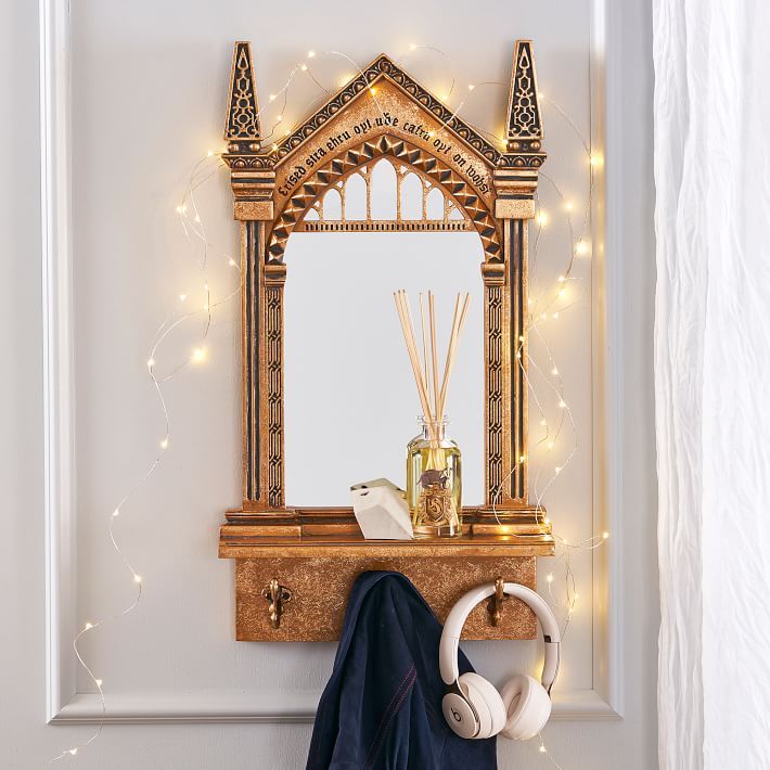 a mirror and some headphones on a shelf in front of a wall with lights