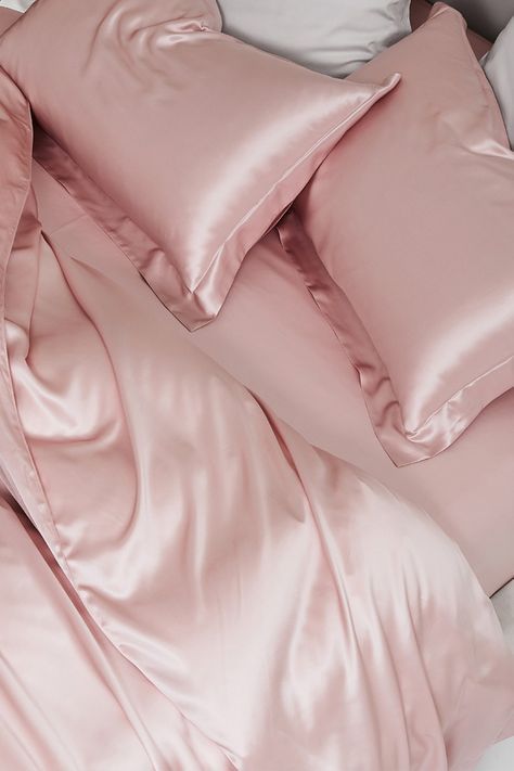 an unmade bed with pink sheets and pillows on top of it, next to a pillow case