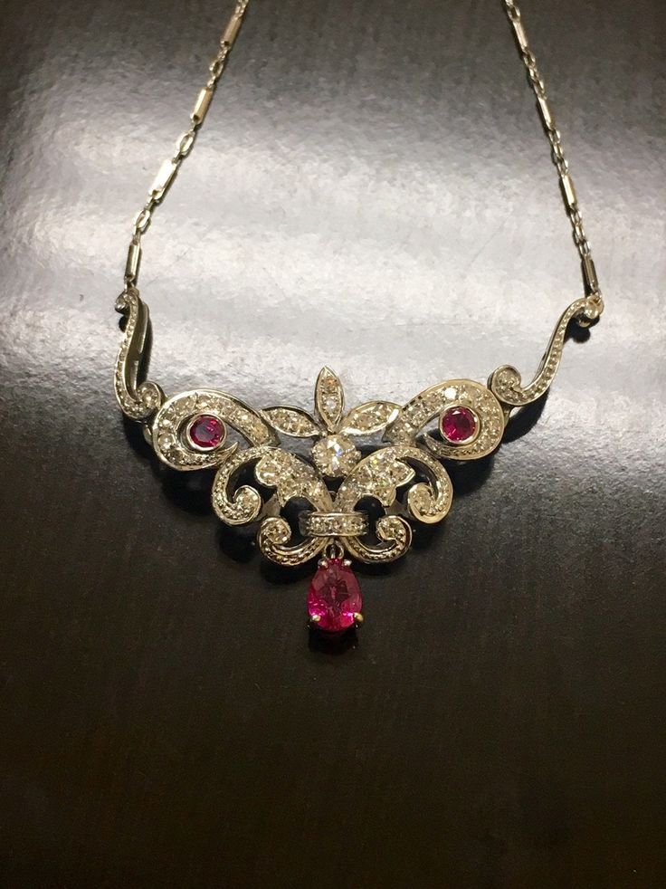 DeKara Designs A Beautiful Timeless 14K White Gold Art Deco Inspired Ruby Diamond Necklace. Metal- 14K White Gold, .583. Stones- 1 Pear Shape Pinkish Red Ruby 0.90 Carats, 2 Round Rubies 0.27 Carats, 44 Round Antique Diamonds G-H Color VS2-SI1 Clarity 1.10 Carats. Handmade Diamond Art Deco Influcned Ruby Diamond Necklace. I have used authentic antique Old European Cut and Miner's Cut diamonds for this necklace. The necklace features a beautiful pear shape ruby that is dangling on the bottom of t Antique Hand Set Necklace For Gift, Formal Ruby Necklace With Hallmark, Oval Fine Jewelry Necklace With Intricate Design, Luxury Diamond Necklace For Collectors, Antique White Gold Gemstone Necklace, Yellow Gold Necklace With Intricate Ruby Design, Diamond Pendant Necklace For Collectors, Collectible Yellow Gold Necklace With Intricate Design, Antique Ruby Necklace For Formal Occasions