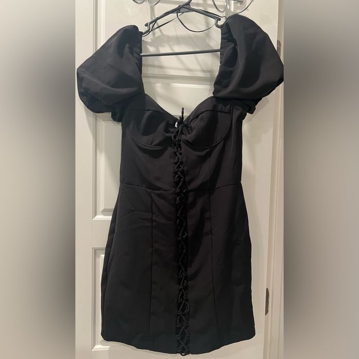 a black dress hanging on a hanger in front of a door with eyeglasses