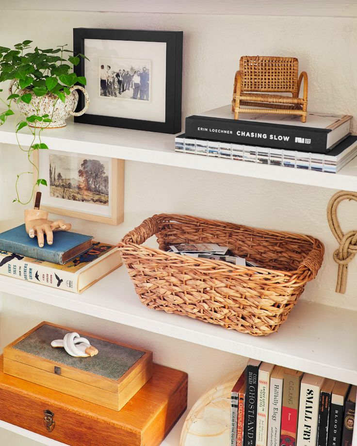 a wicker basket sits on top of a book shelf next to books and other items