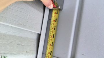 a person measuring the width of a wall with a tape measure