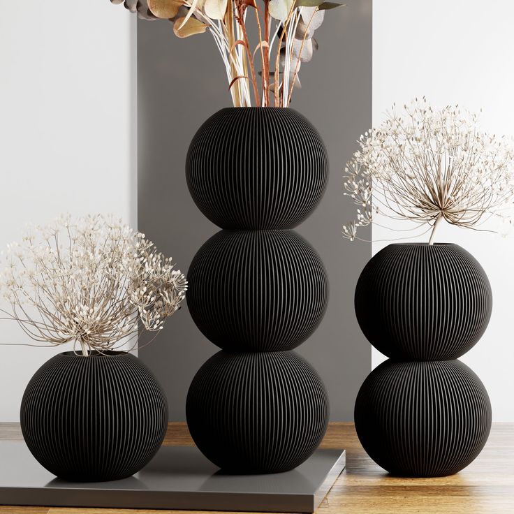 three black vases with dried flowers in them