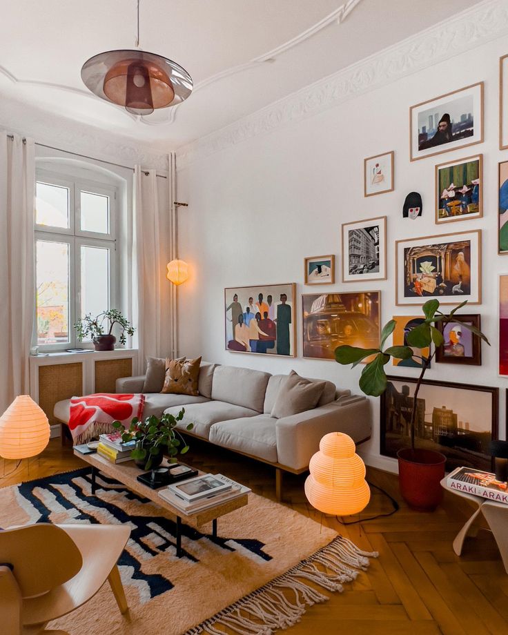 a living room filled with lots of furniture and pictures on the wall above it's windows