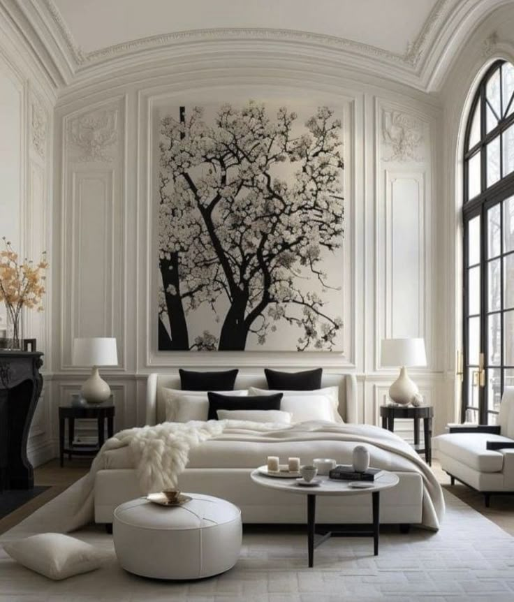 a white bedroom with black and white decor on the wall, large painting above the bed