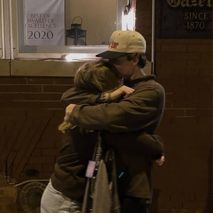 two people hugging each other in front of a building with a sign on the door